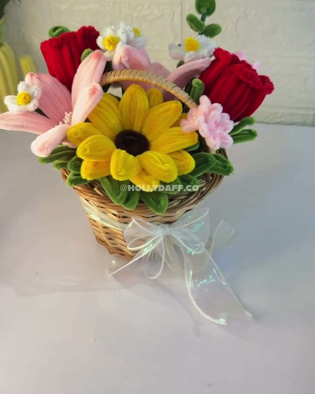 Cane basket filled with a handmade sunflower, lilies and red roses