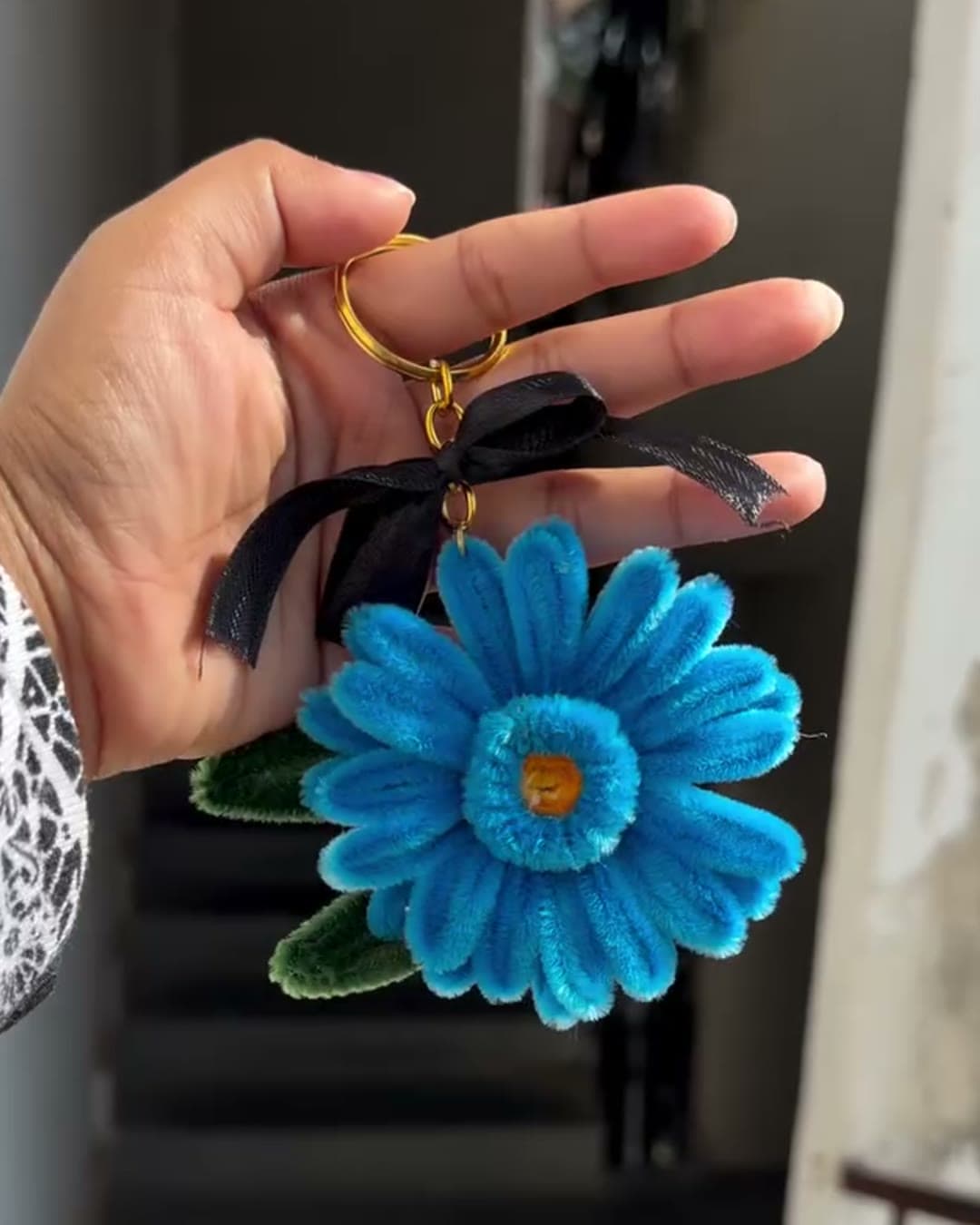 Blue gerbera flower keychain held in hand